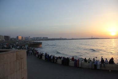 カサブランカのハッサン2世モスクの海岸沿いで夕日を眺めるたくさんの人
