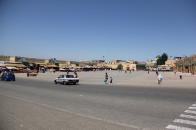 日差しの強い広場で日陰を探す旅人