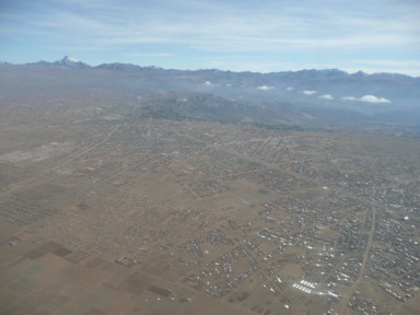 飛行機から見るエルアルトの平らな大地に広がる街と接するラパスの様子