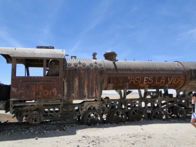 ウユニの列車の墓場のセメントリオ・デ・トレンスに傾いた蒸気機関車の姿