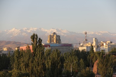 ビシュケクの低いビル群と朝日を浴びてオレンジに染まる雪山
