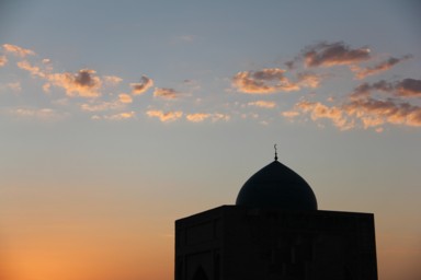 ブハラの黄昏の時間にオレンジと濃紺の空に浮かび上がるモスクの光景