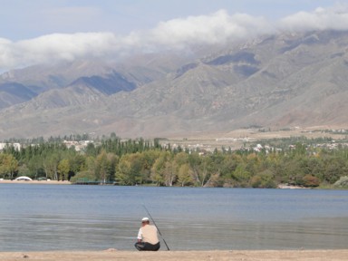 イシククル湖の絶景を前に釣りをする人