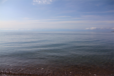 波のない穏やかなイシククル湖の湖畔