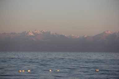 イシククル湖の対岸の夕暮れに染まりオレンジ色をする雪をかぶった天山山脈