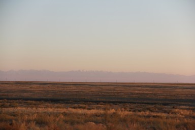 カザフスタンの何もない真っ平らな大地とはるか遠くに見える連なった山