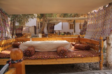 ヒヴァのベットのようなフレームにクッションとかが置かれたチャイハナの光景