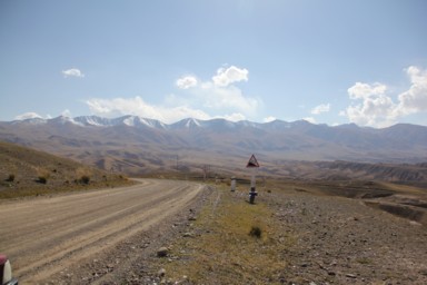 コチコルの土の道の峠を越えた先にある雪をかぶった山々