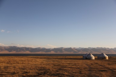 ソンクル湖と影が伸びるオレンジがかったユルタの景色