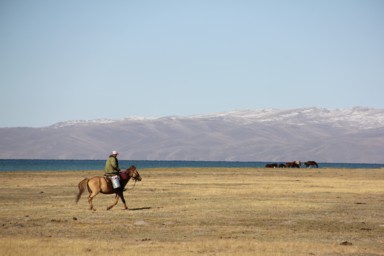 ソンコル湖で暮らす人の馬で移動している光景