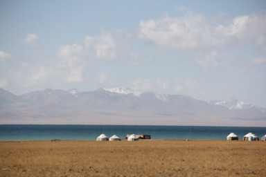 緑がかったソンコル湖と白いテントと山々