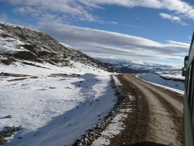 早朝の舗装されていない茶色い道と銀世界