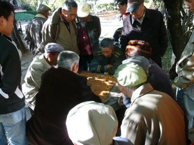 麗江の街角で将棋みたいなのを指す人と見ている人々