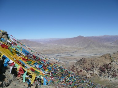 カラフルなタルチョの旗と無機質で色のない大地