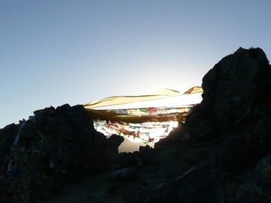 太陽を浴びてオレンジに輝くタクツェのガンデン寺のカラフルな旗