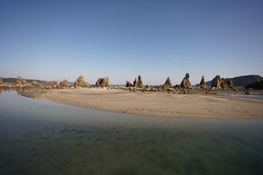 海に岩の柱が延びる橋杭岩