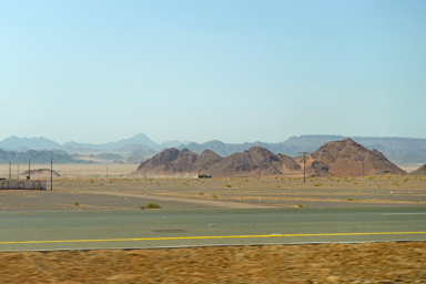 砂漠と岩山の大自然の中をジープが砂煙をあげながら疾走