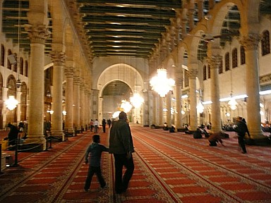 ウマイヤド・モスク内部の赤いじゅうたんの上で祈る人々の静寂な風景