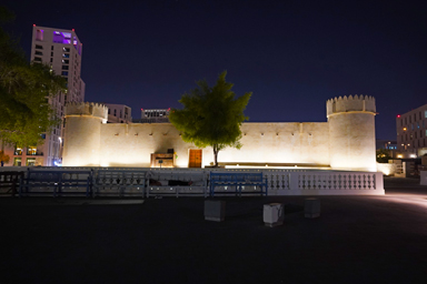 ビルに囲まれたドーハ・フォートの夜の派手なライトアップ