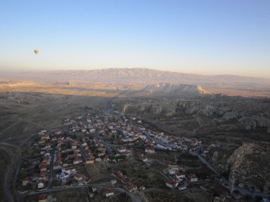 朝日が昇る前のカッパドキアの赤屋根の小さな町を上から気球で通過