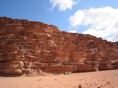 見たことのない岩山の前に小さなジープ