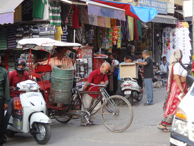 リキシャに重そうなドラム缶をのせて押して運ぶおじいちゃん