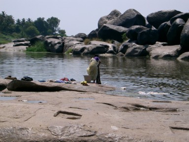 ハンピのトゥンガバドラー川で洗濯する女性の風景