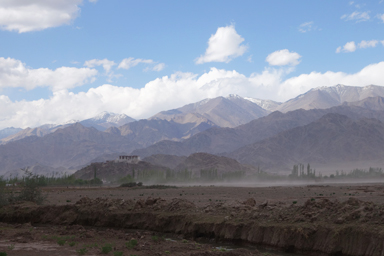 遠くから見た丘の上のスタクナゴンパと周りの山々の風景