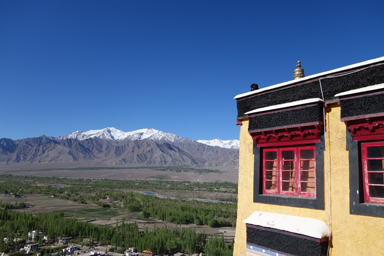 ティクセ寺の赤い窓と周りの白い山と青い空の景色