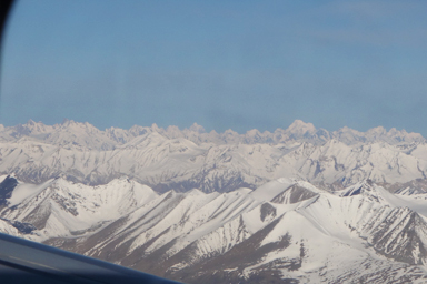 飛行機の窓から幾重にも空へ伸びるヒマラヤの姿