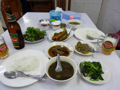 いろんなミャンマーの小皿料理とビールがテーブルにのった光景