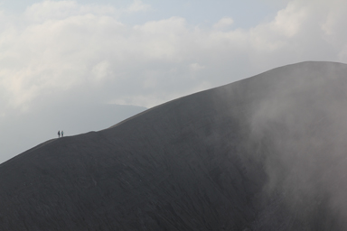 ブロモ山の火口の細いふちを歩く人