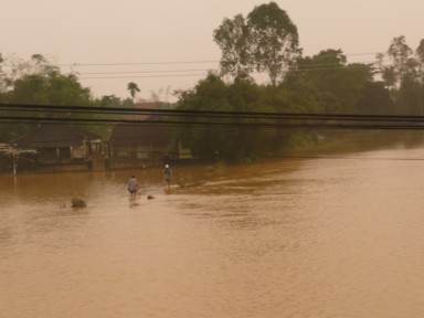 熱帯の雨で水浸しになった町を進むバス