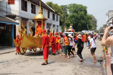 高僧をのせた乗り物を引く僧に控えめに水をかける
