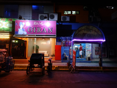 日本語が書かれた看板の夜のお店が並ぶ