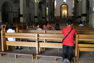 マニラ大聖堂で手を合わせひざまずいて祈る人々