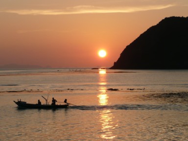 ハードリンのサンセットビーチで夕日の海に漁をする小さな船の様子
