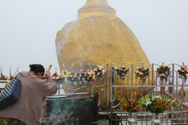 男性のみが近づける金色の岩に外から祈る女性