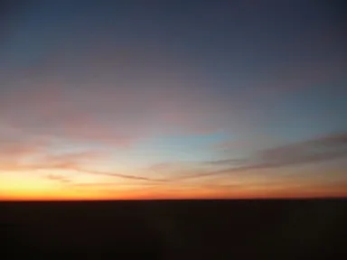 オレンジや青に染まる朝焼けに包まれた平らな砂漠の景色
