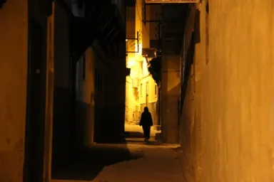 フェズのオレンジの柔らかいライトで染まる夜の路地に歩く人