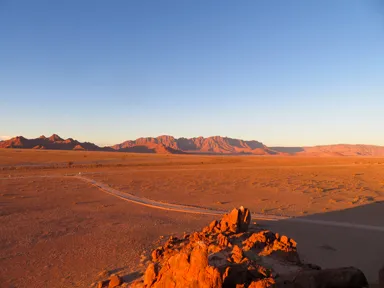 ナミブ砂漠の夕暮れに大地が赤く染まる光景