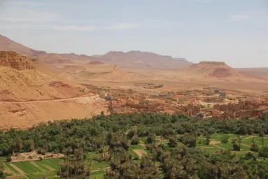カスバ街道の荒れた大地に緑あふれる村がたたずむ光景
