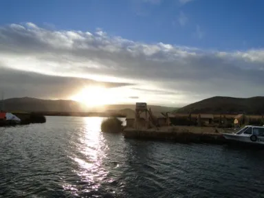 チチカカ湖に浮かぶウロス島で夕日がプーノの街に沈む様子