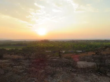 サンミゲル・デ・アジェンデの郊外の大地に沈む夕日とゆっくり走る貨物列車の風景