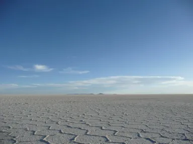 ウユニ塩湖の唯一見える遠くの小さな山と地面が白く五角形や六角形になった光景