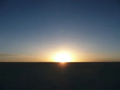 ウユニ塩湖の海とも違う直線の地平線に太陽が沈む様子