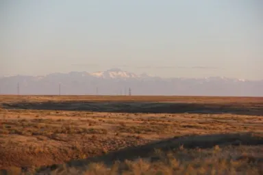 カザフスタンの何もない真っ平らな大地とはるか遠くに見える雪山