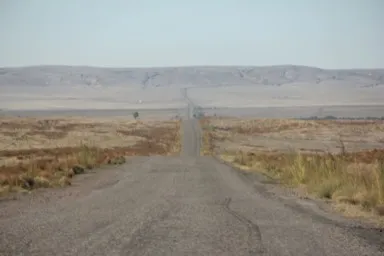 カザフスタンの荒涼とした大地を果てしなくのびる一本道の風景