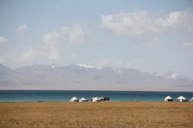 緑がかったソンコル湖と白いテントと山々