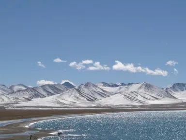 ナムツォの輝く湖と雪の山々と真っ青な空